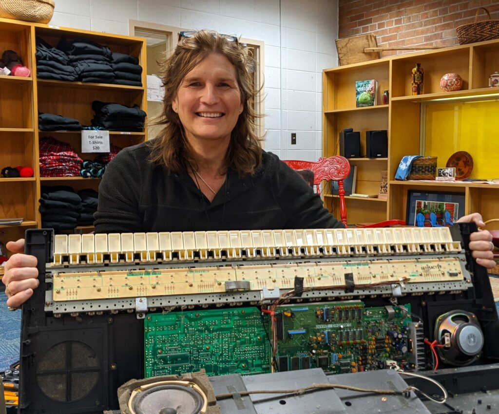 Dana Vannen Anderson holds a repaired keyboard at Dare to Repair community event