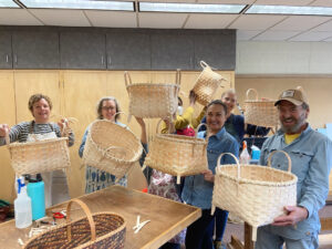 A group of smiling students upcoming completion of their Wool Drying Baskets.