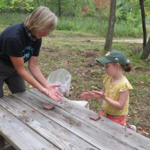 A marine mills folk school volunteer assists a child in the forest outside of our school